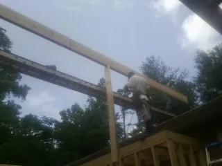 Carpenter setting a ridge beam over a new addition frame — Ice Dam Removal by Roofing Brothers in White Lake