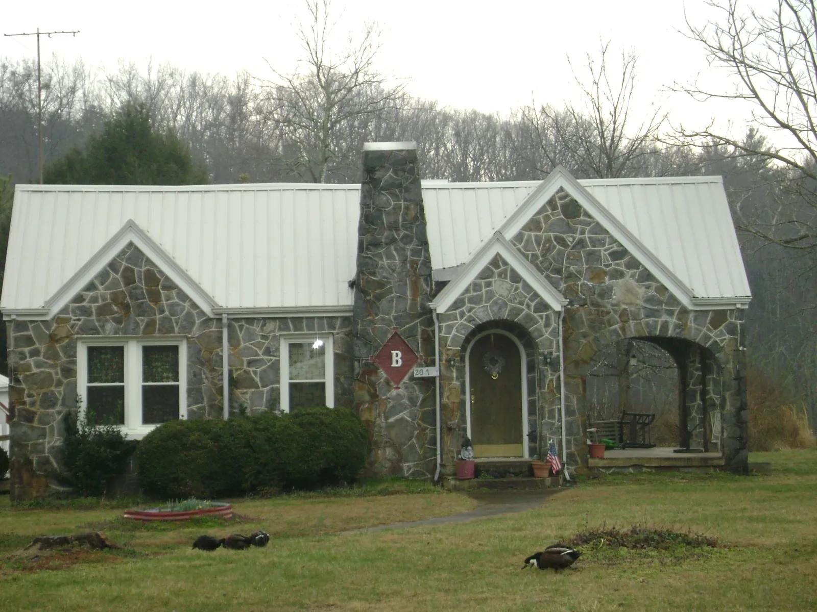 White metal roof on a stone cottage with steep gables in White Lake