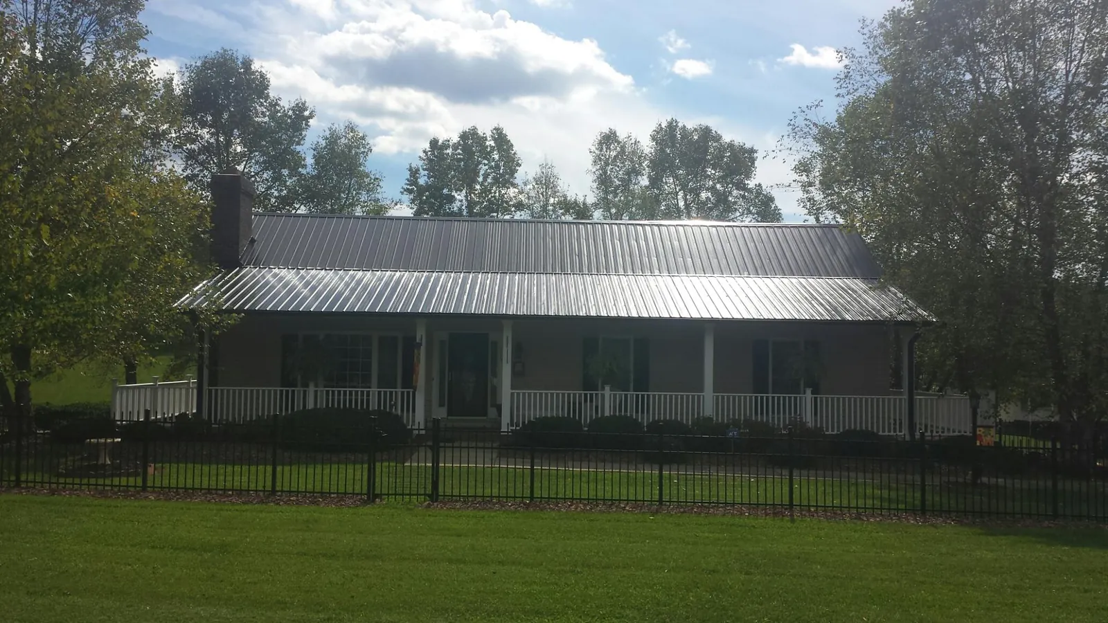 Gray metal roof on a brick ranch with a full width front porch — Gutter Guard Installation work by our crew in White Lake