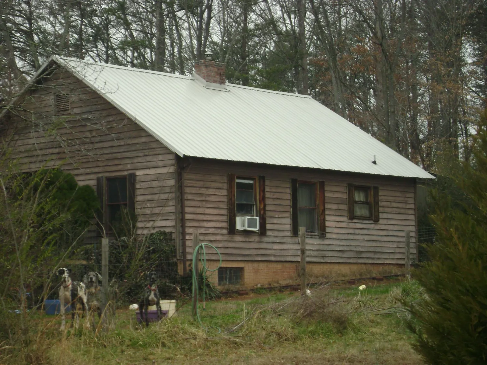 White metal roof on an old wood sided farmhouse, from a Metal Roof Installation job in White Lake