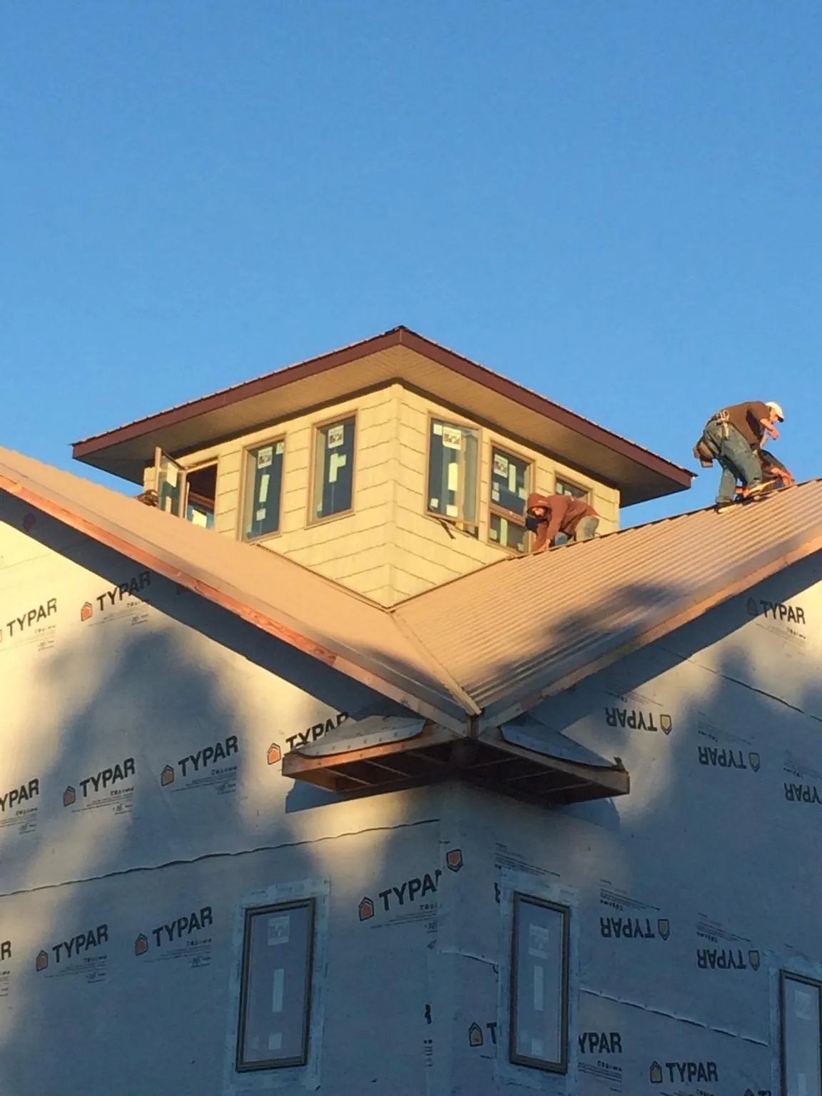 Roofers working around a rooftop cupola on a new metal roof at sunset — Roof Waterproofing in White Lake by Roofing Brothers